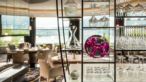 Un hall d’hôtel moderne avec une vitrine exposant des verres à vin et un ballon rose décoratif.