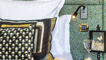A neatly made bed with patterned pillows and a bedside table with a lamp, clock, and decorative items.