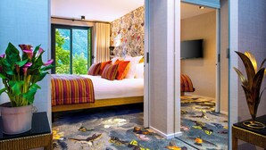 Une chambre d’hôtel avec un lit, une plante en pot, un téléviseur et une moquette à motifs.