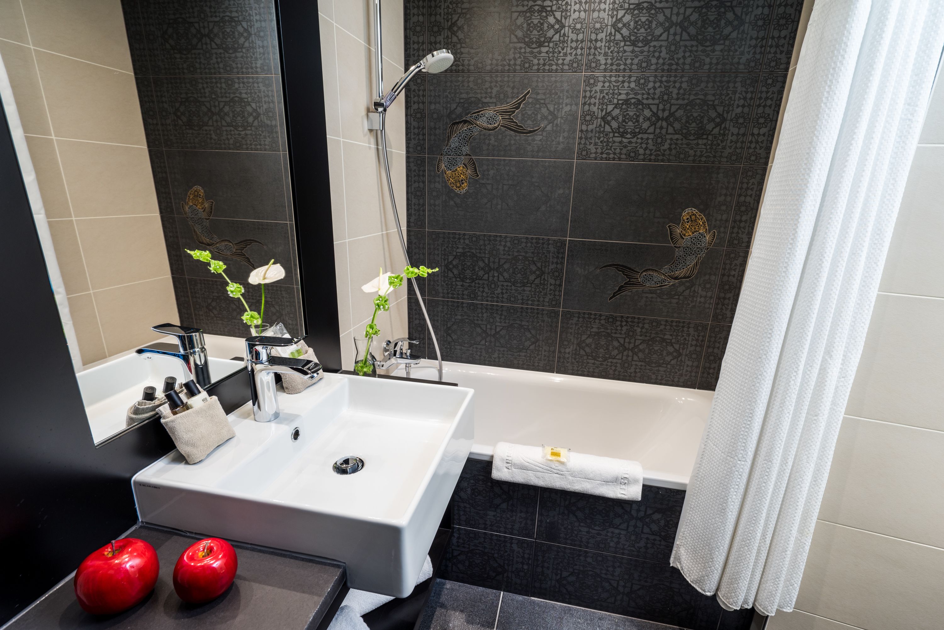 A modern bathroom with a white sink, a bathtub, and decorative fish tiles.