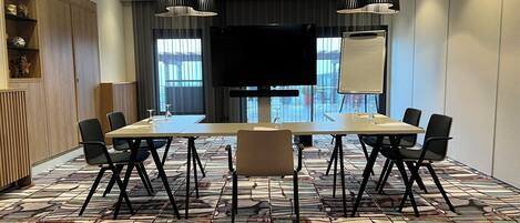 A conference room with a long table, chairs, a projector screen, and a whiteboard.
