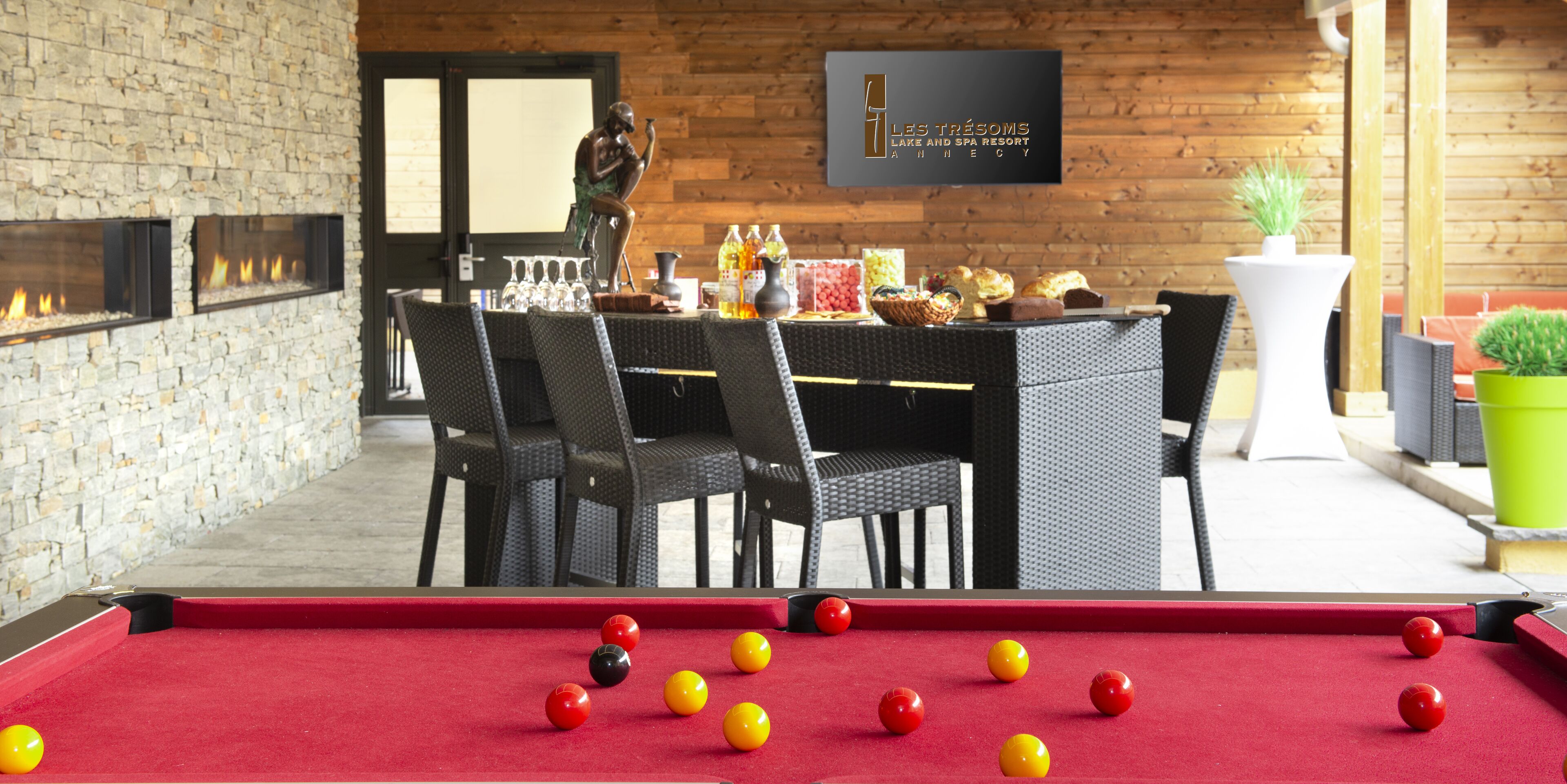 A pool table with balls, a statue, and a bar area with chairs and bottles.