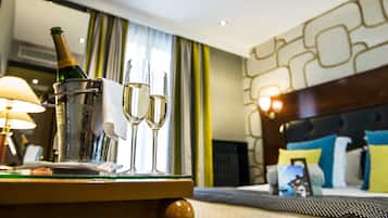 Een hotelkamer met een bed, een nachtkastje met een fles champagne en twee glazen, en een lamp.
