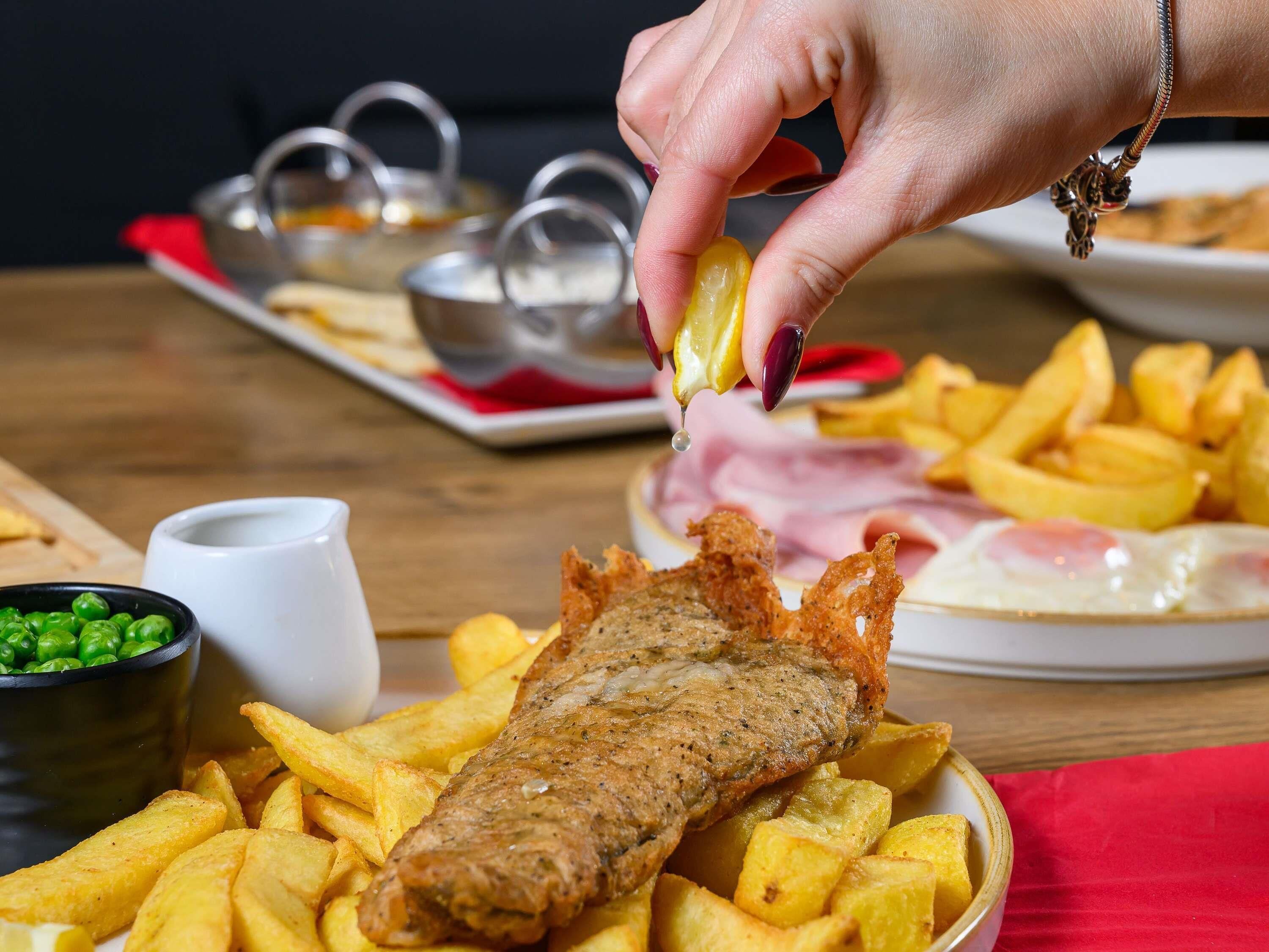 Ein Gericht mit Fisch, Pommes und einer Soße zum Dippen.