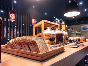Een bakkerijvitrine met sneetjes brood en potten met beleg.