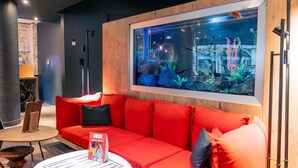 Un intérieur moderne avec un canapé rouge, une table ronde blanche et un grand aquarium.