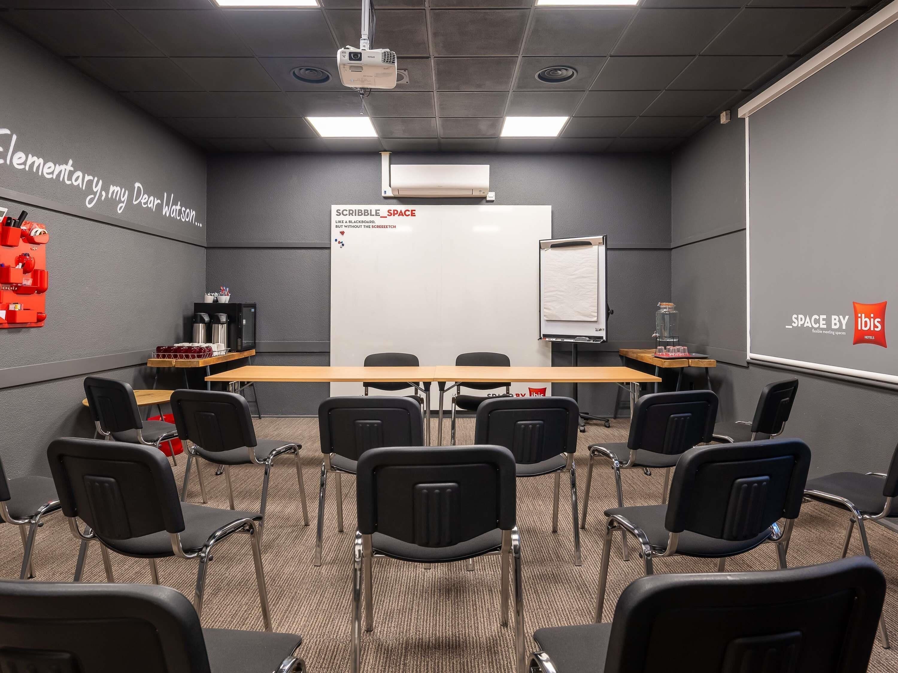 A conference room with a whiteboard, projector, and seating arrangement.