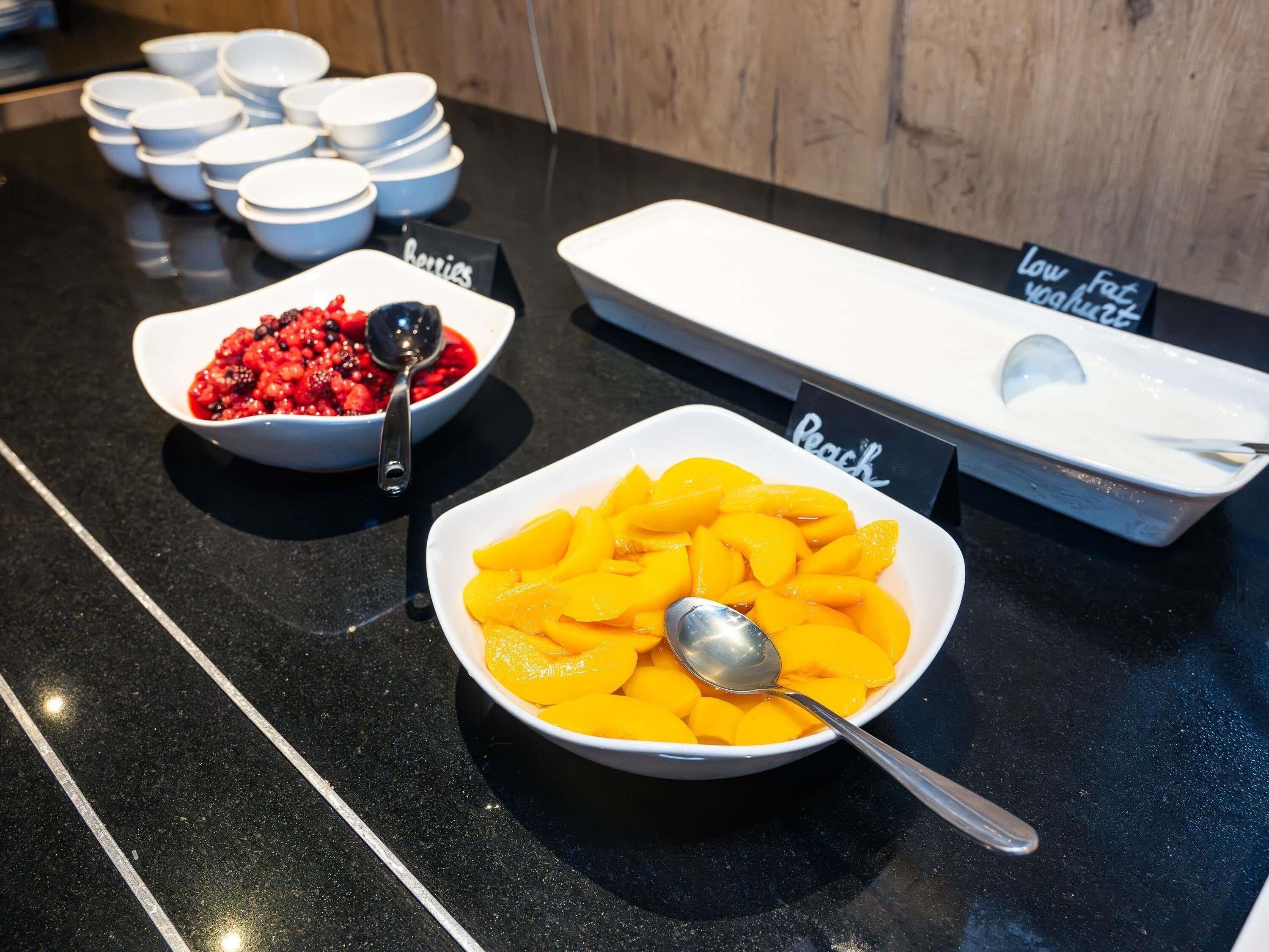 A buffet table with bowls of berries and peaches, and signs indicating low fat and low sugar options.
