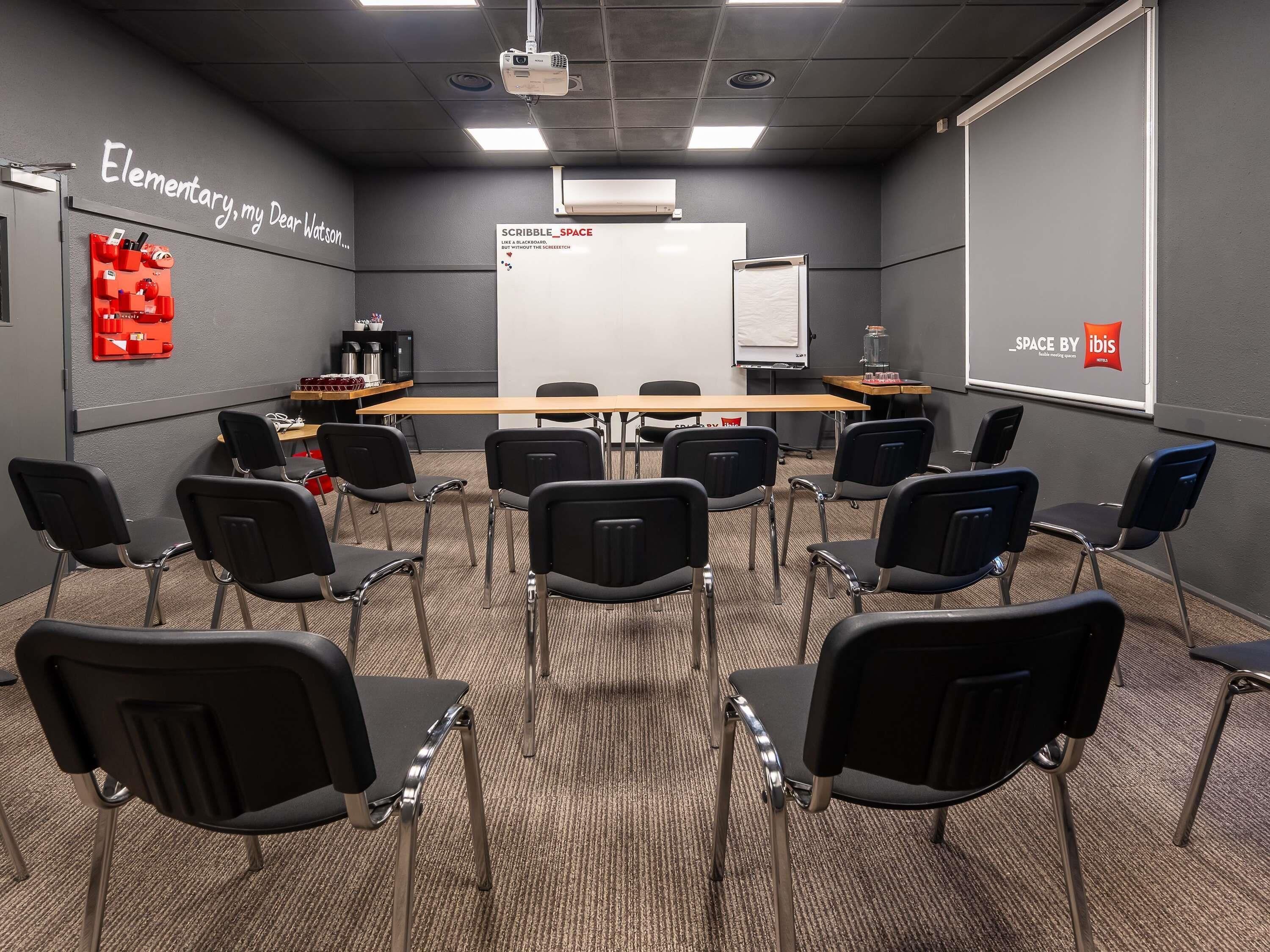 A conference room with a whiteboard, projector, and seating arrangement.