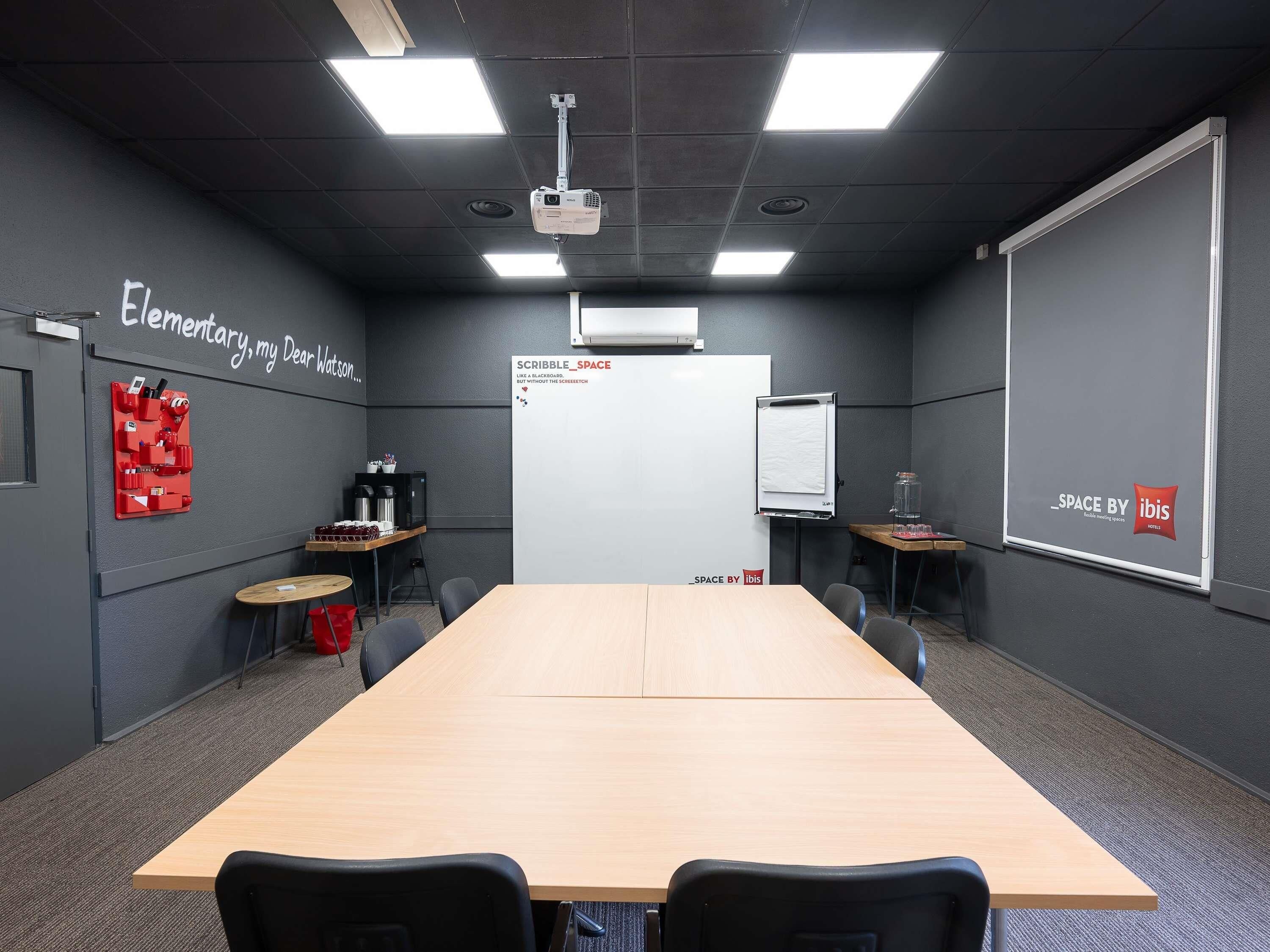 A conference room with a long table, chairs, a whiteboard, and a projector.