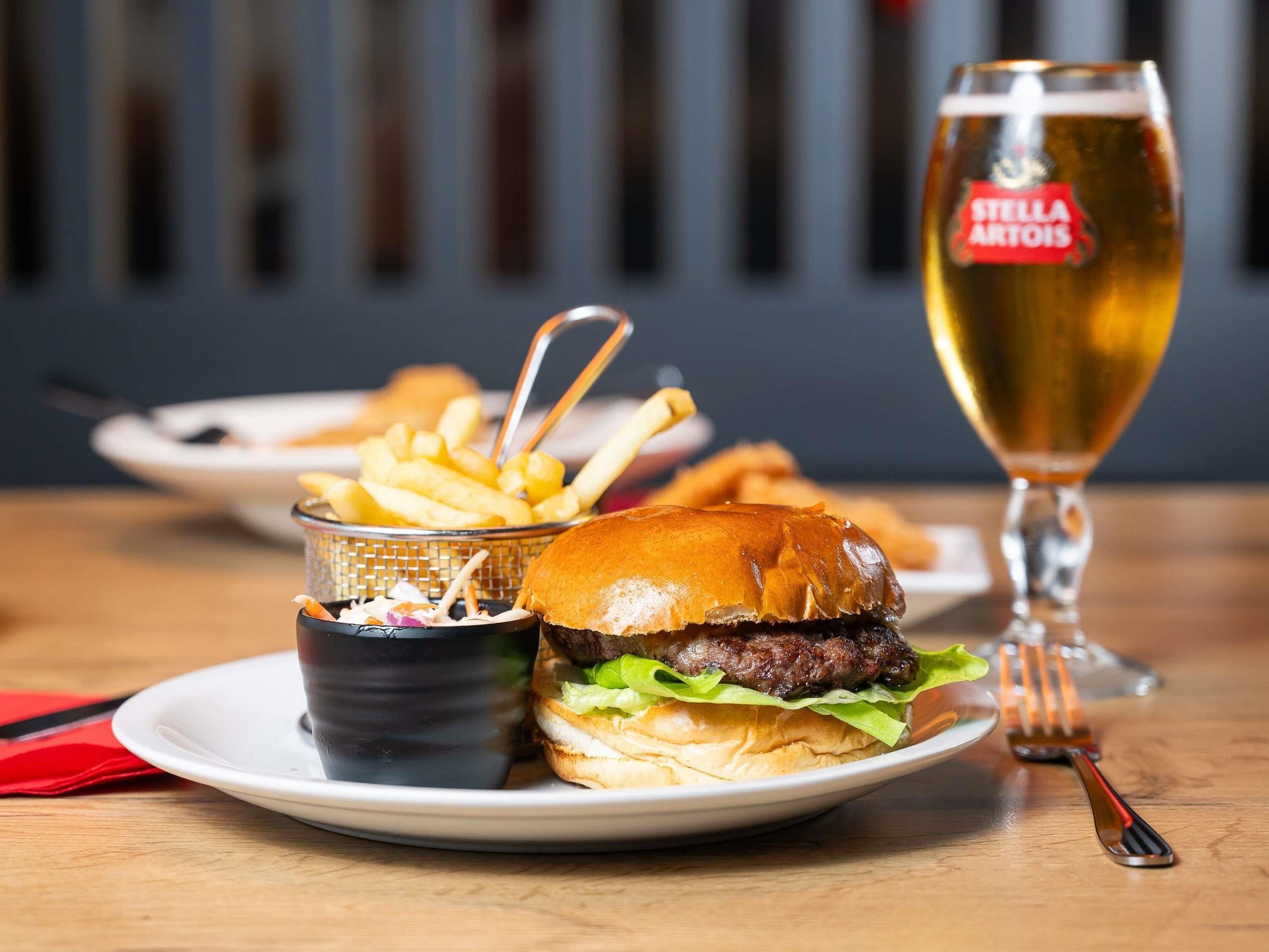 Un hamburger accompagné de frites et d’un verre de bière, le tout posé sur une table.