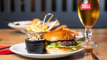 Una hamburguesa amb patates i un got de cervesa damunt un taulell.