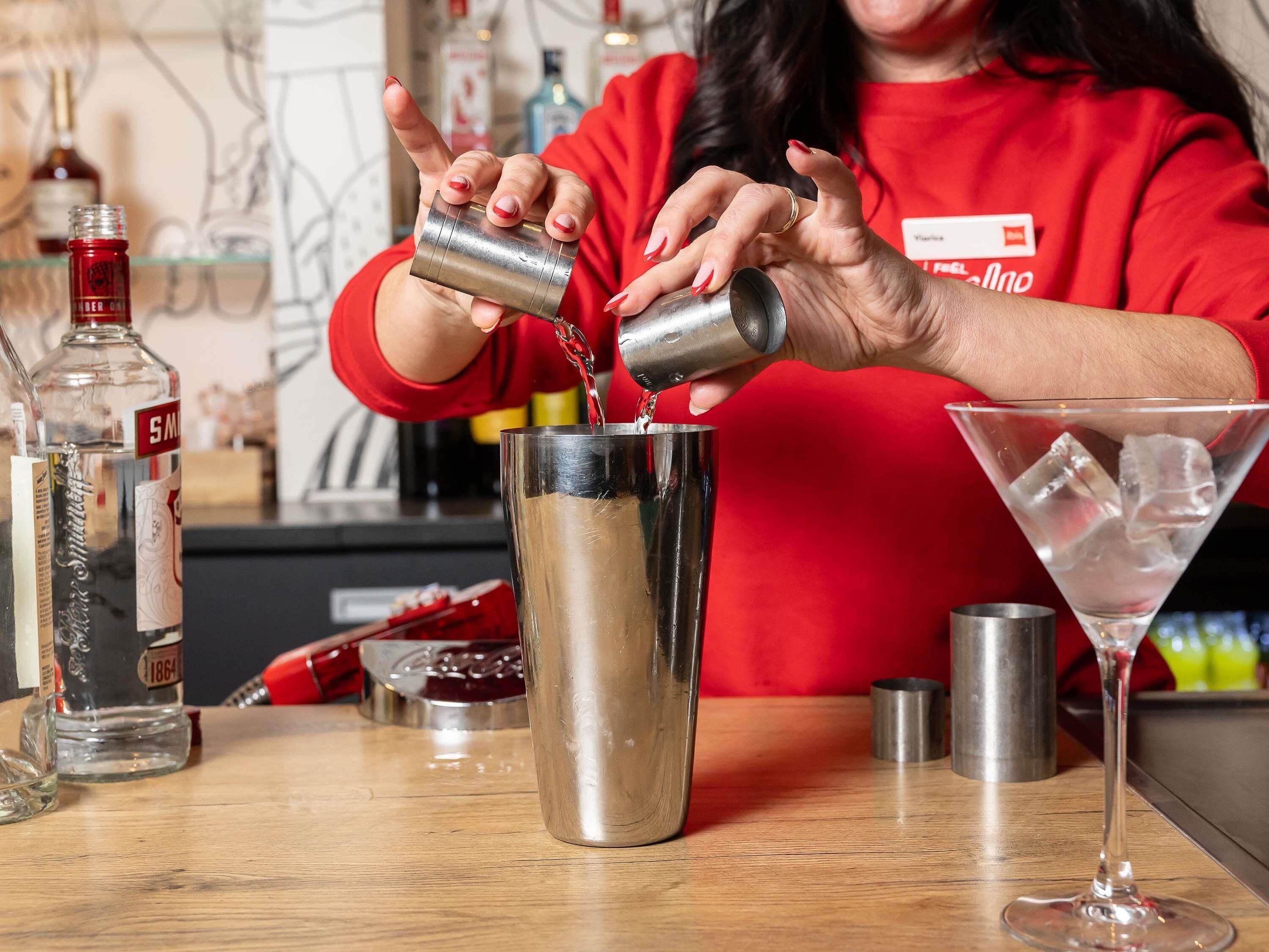 A bartender pouring a drink into a shaker.