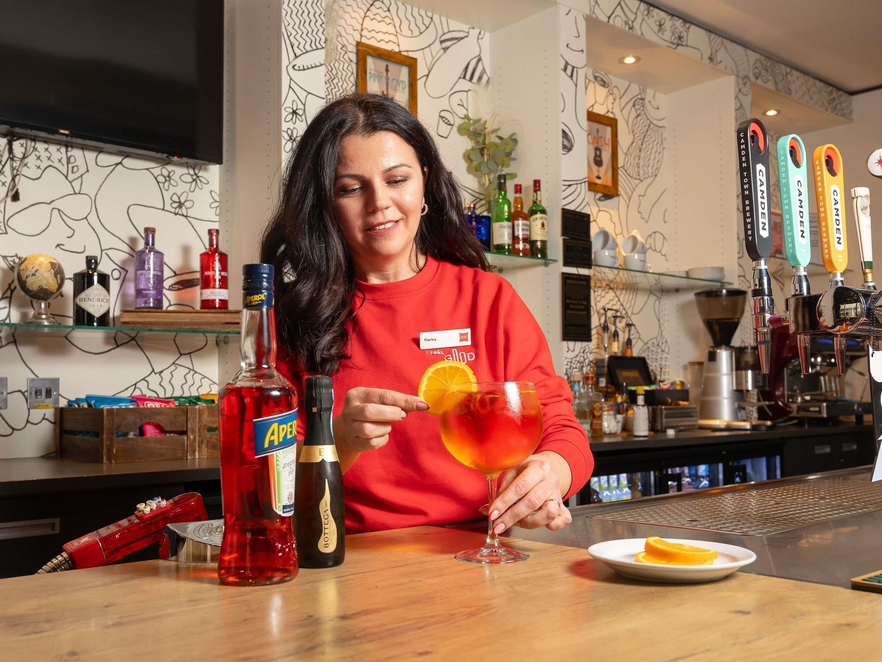 Ein Barkeeper bereitet ein Getränk mit Flaschen Aperol, Hendrick's und Bottega zu.