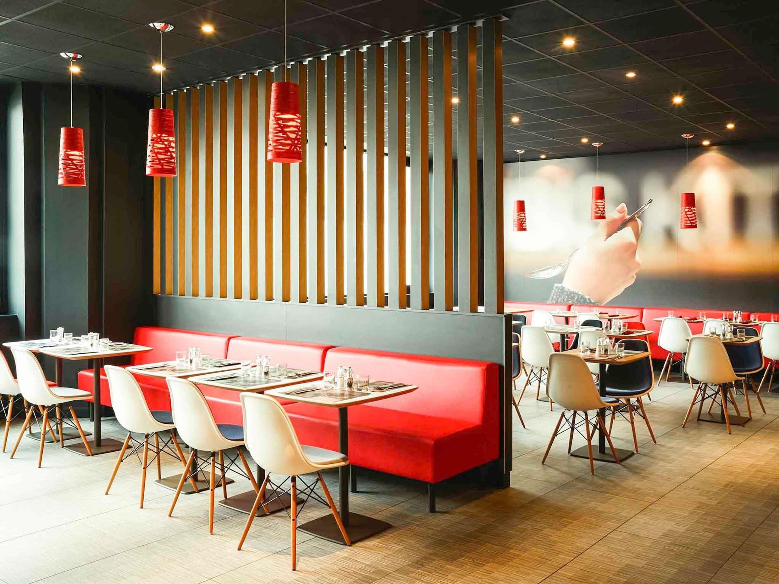 Interior de restaurante con asientos rojos, listones de madera y faroles rojos colgantes.