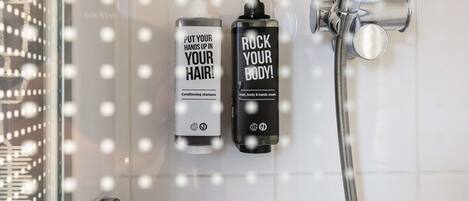 Two bottles of hair and body wash in a shower area with a glass door.