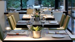 A restaurant with tables set for dining, each with a wine glass, a plate, and cutlery.