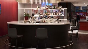A modern bar area with a round counter, multiple shelves of liquor bottles, and bar stools.