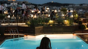 A rooftop pool with a view of a cityscape at dusk.