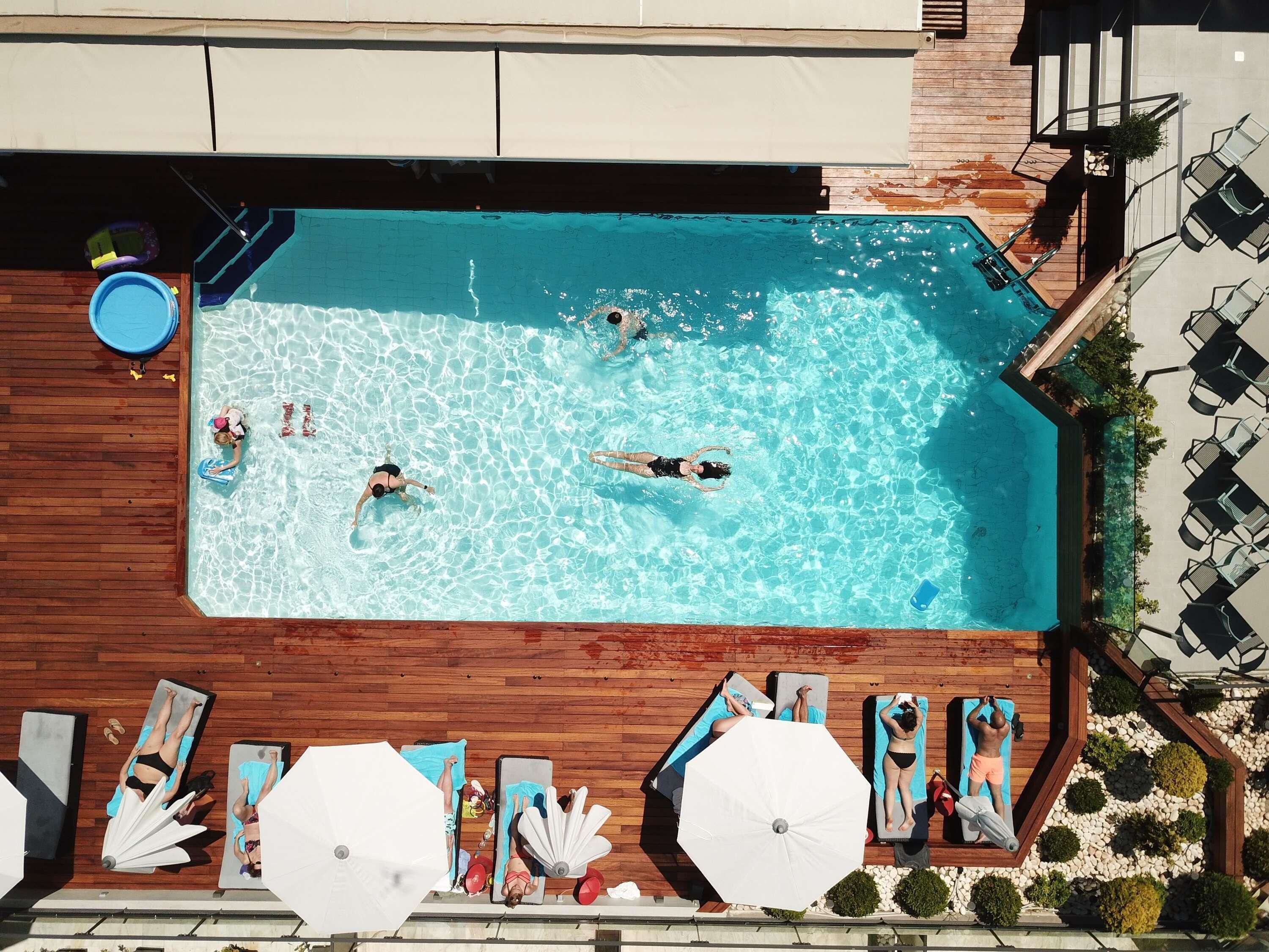 An outdoor swimming pool with people swimming and sunbathing.