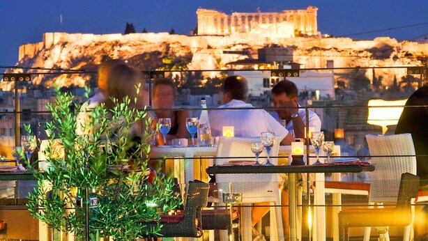 A rooftop restaurant with tables and chairs, overlooking a historic building.