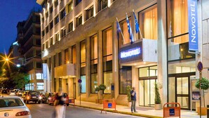 A Novotel hotel with a modern facade, multiple flags, and a well-lit entrance.