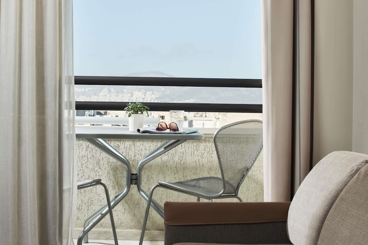 A balcony with a table, a chair, a potted plant, and sunglasses.