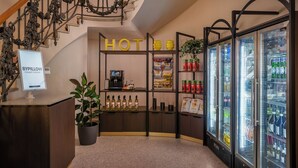 A hotel reception area with a digital kiosk, a self-service beverage station, and a refrigerator stocked with drinks. - BYPILLOW Grand Central (Padova)