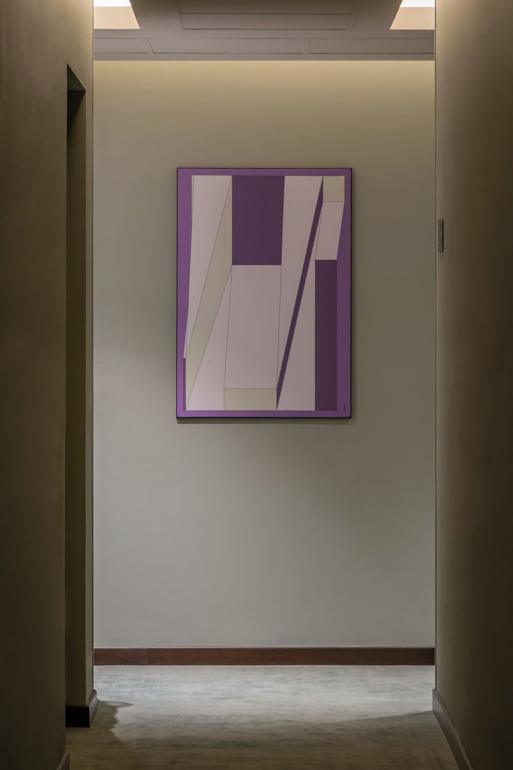 A hallway with a framed abstract painting on the wall.