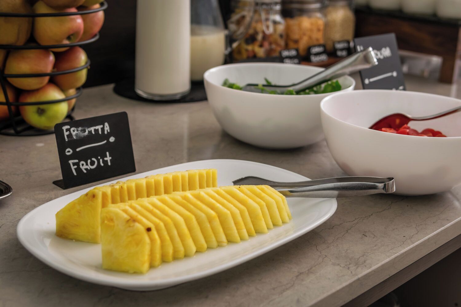 Presentación de frutas con piña en rodajas, ensalada en un tazón y frutos rojos.