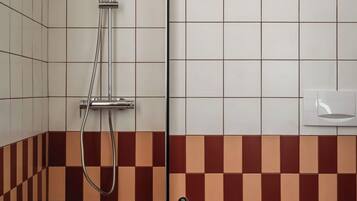 Un baño con ducha, bidé y paredes de azulejos.