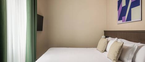 Una habitación de hotel con una cama, un televisor de pared y un cuadro.