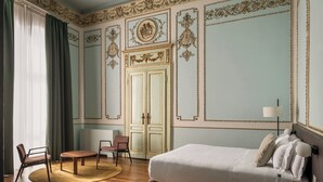 A room with a bed, two chairs, a round table, a lamp, and a wardrobe. - BYPILLOW Grand Central (Padova)