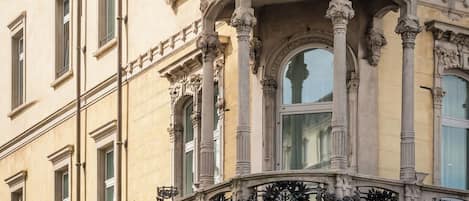 Un edificio con balcones ornamentados, grandes ventanales y detalles arquitectónicos clásicos.