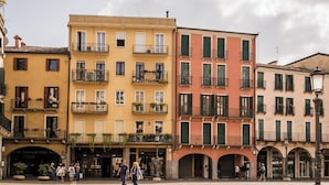 A street with multi-story buildings, balconies with plants, and storefronts. - BYPILLOW Grand Central (Padova)