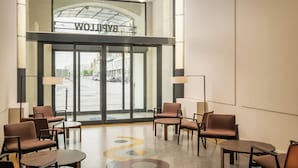 A hotel lobby with a glass entrance, seating area, and a visible sign above the doors. - BYPILLOW Grand Central (Padova)