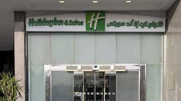 The entrance to Holiday Inn & Suites with a glass door and a green 'H' logo.