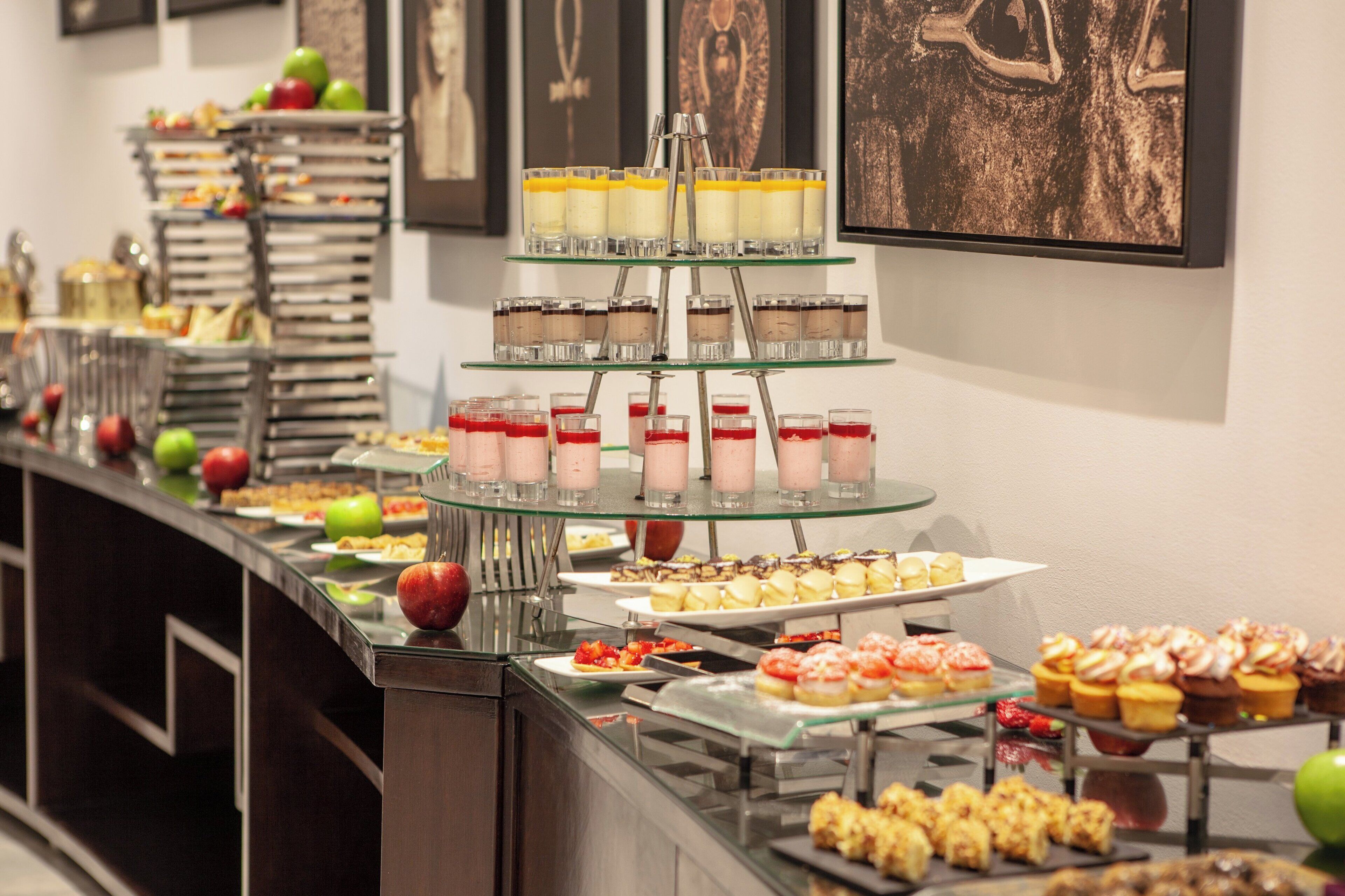 A buffet with various food items and desserts, including layered desserts and fruit.