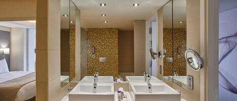 Un baño de hotel con dos lavamanos, un espejo grande y una zona de ducha.