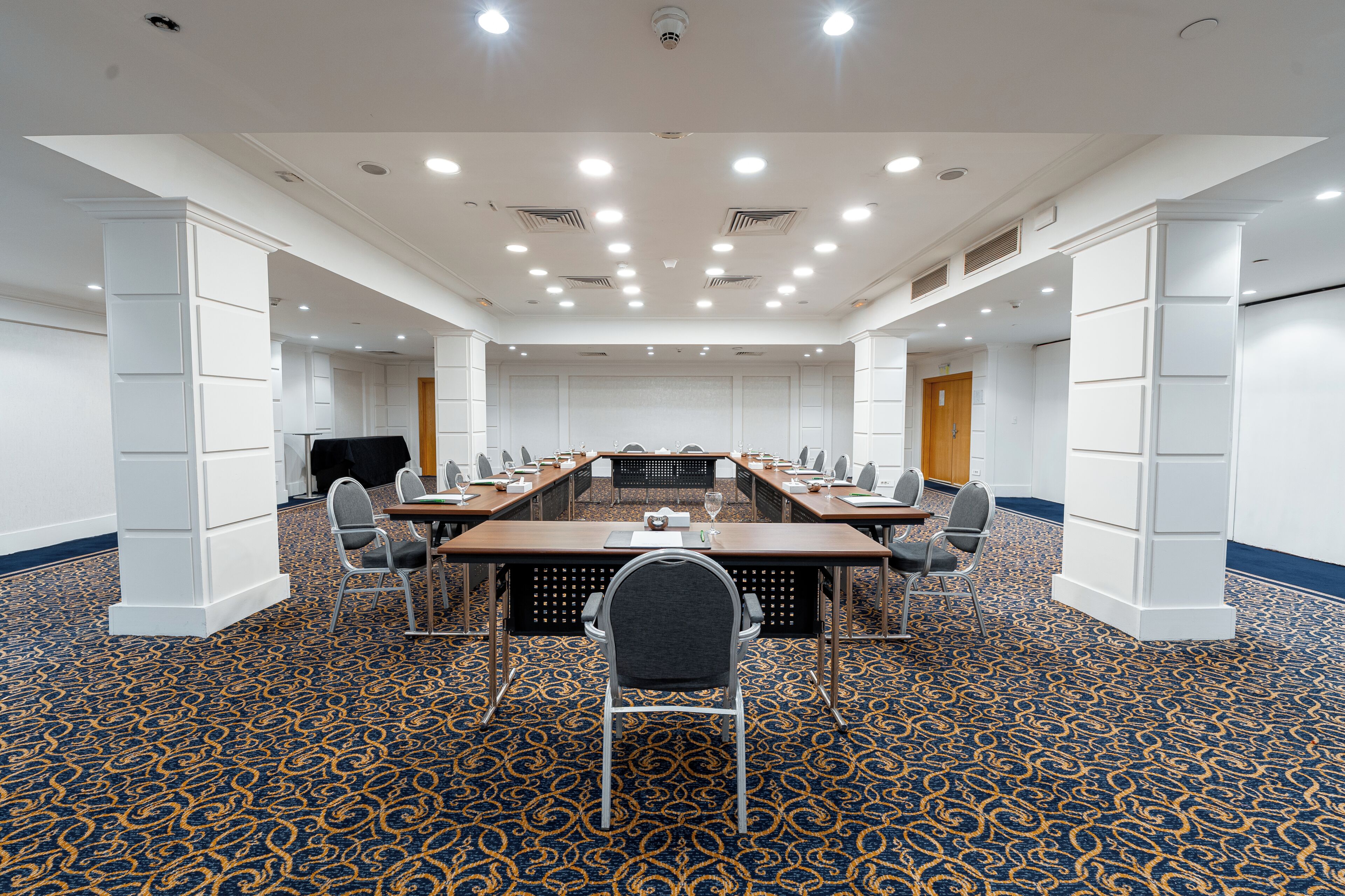 A conference room with a long table, chairs, and a carpeted floor.