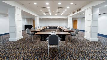 A conference room with a long table, chairs, and a carpeted floor.