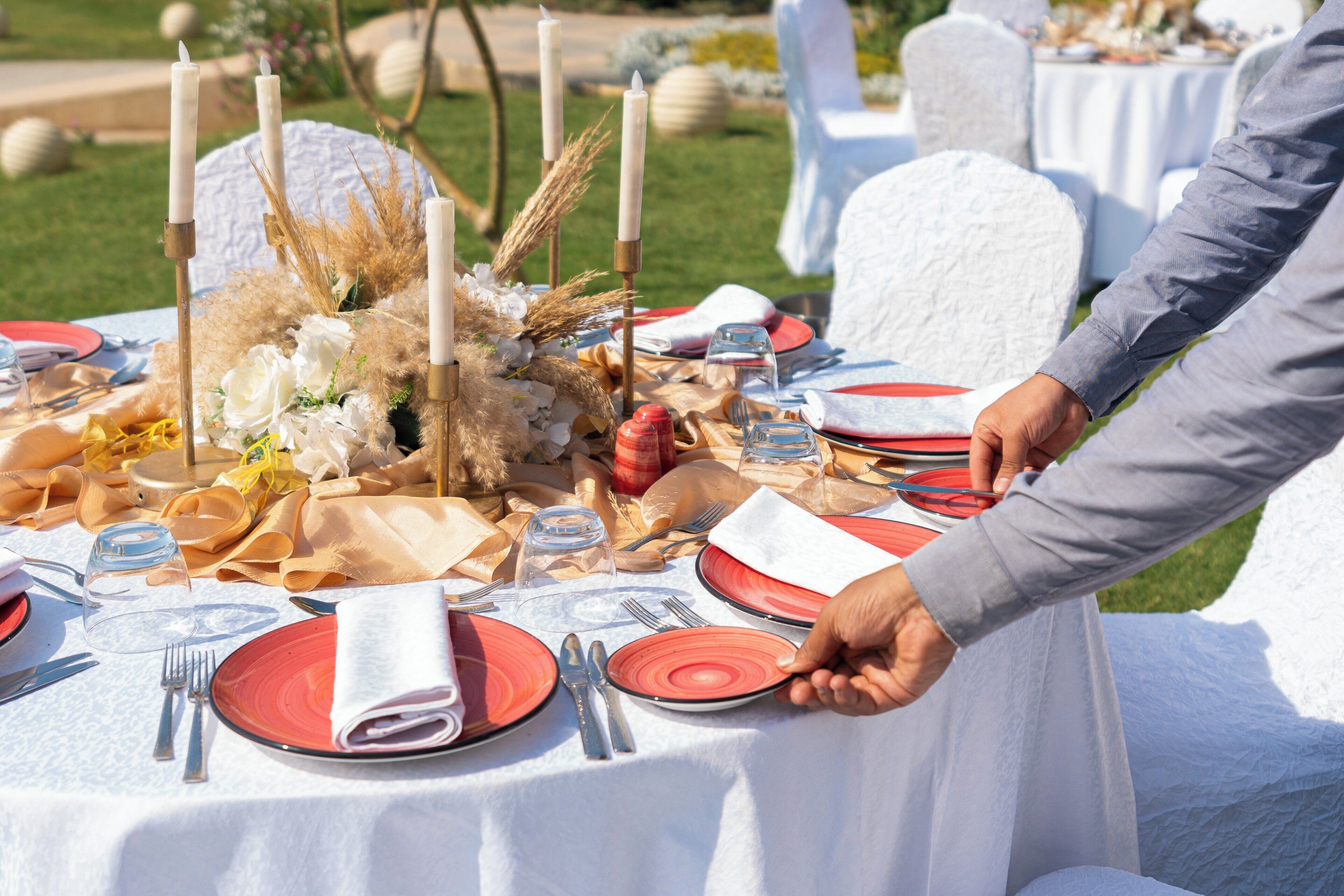 A table set with red plates, white napkins, and candles.