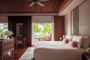 A spacious bedroom with a large bed, a desk, and a chair. There is a balcony with a view of palm trees. - Anantara Hua Hin Resort (Hua Hin)