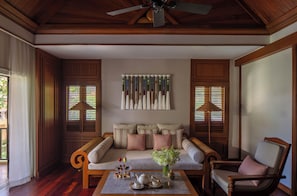 A cozy living room with a sofa, armchairs, a coffee table with tea set, and a wall-mounted art piece.