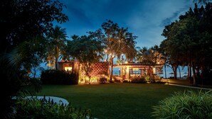 A well-lit resort with a pool, palm trees, and a beach view.