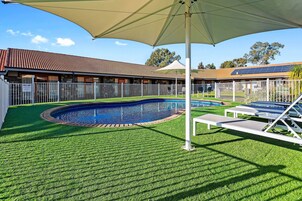 Una piscina al aire libre, sombrillas, sillones reclinables de piscina