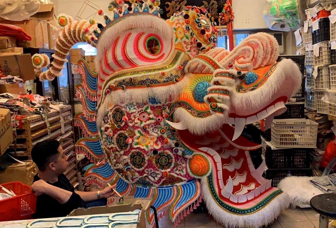 Un traje colorido de danza del león en un área de almacenamiento con cajas y contenedores.