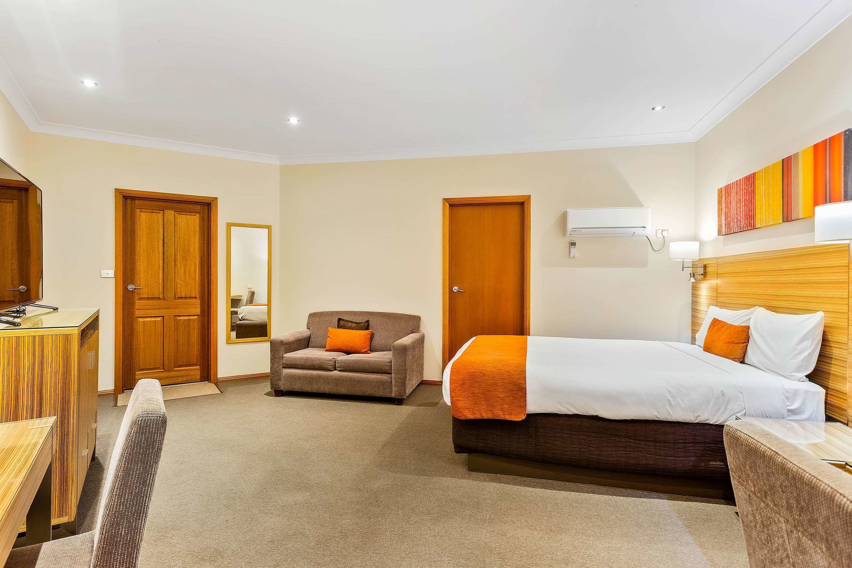 A hotel room with a bed, a desk, a chair, and a sofa.