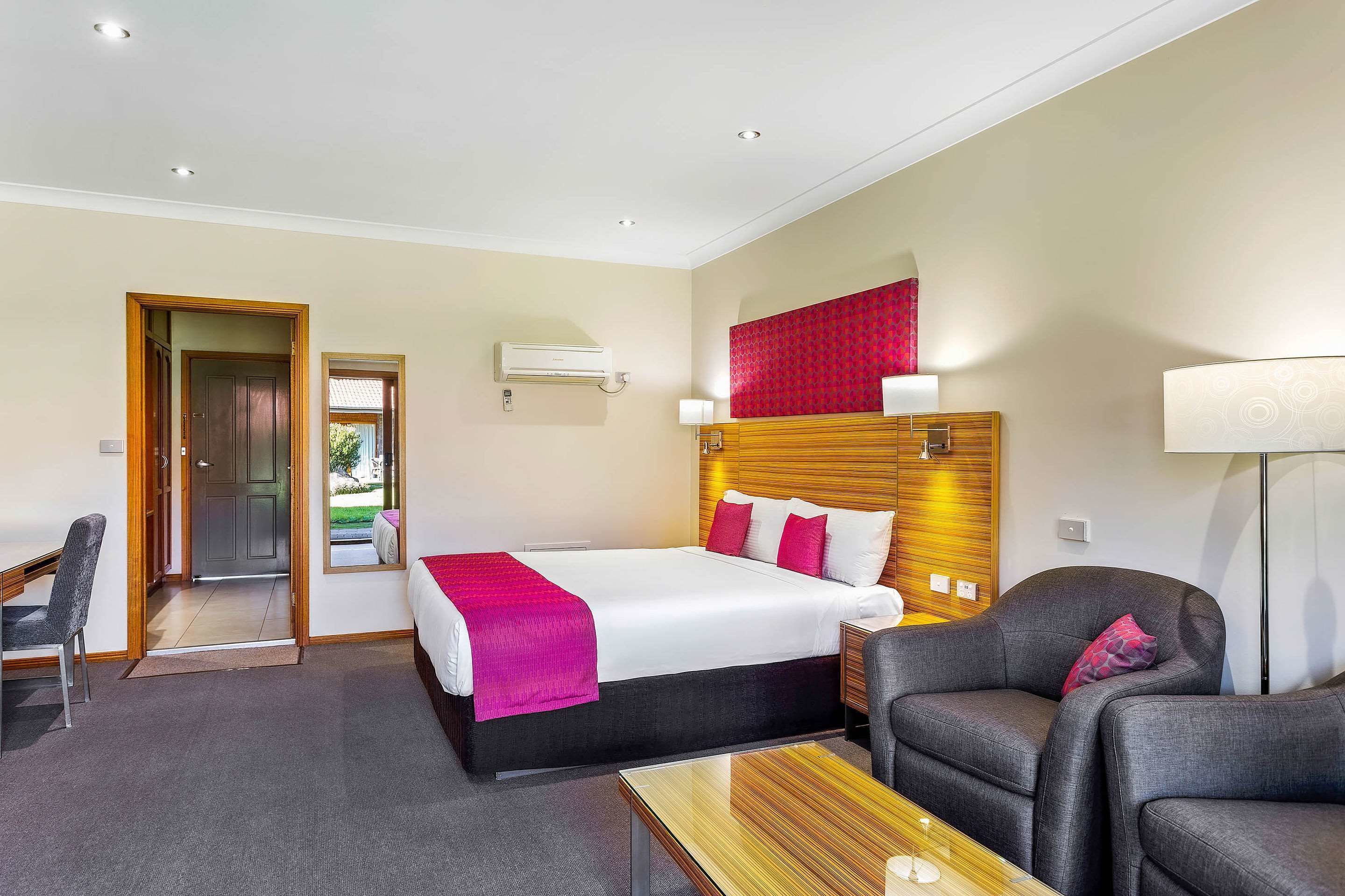 Een hotelkamer met een bed, een bureau, een stoel en een lamp.
