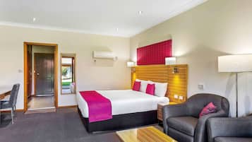 A hotel room with a bed, a desk, a chair, and a lamp.